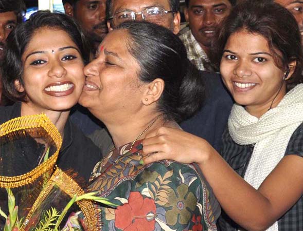Woman karateka Valena Valentina (Left) gets a kiss from her mother while her sister looks on in Bhubaneswar.
